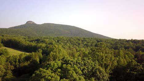 aerial of pilot mountain in background as drone pushes toward the summit in 4k