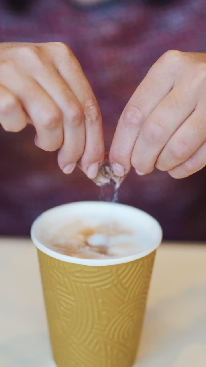 Girl adding sugar to her coffee in a fast food restaurant. Coffee break in cafe Vertical video