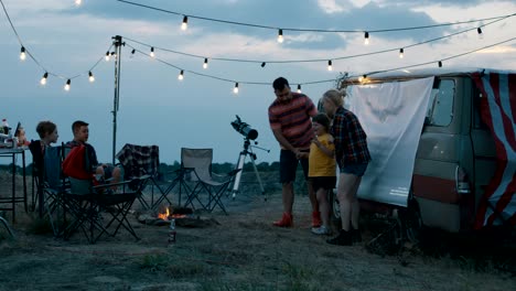 people with children playing charades in campsite