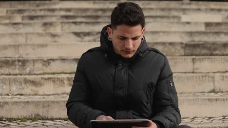 focused young man using tablet outdoor