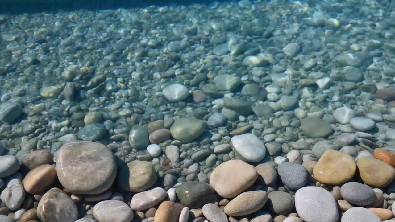 Acqua limpida che scorre su ciottoli lisci su una spiaggia