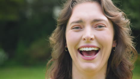 laughing joyfully, woman enjoying sunny day outdoors in park, feeling happy