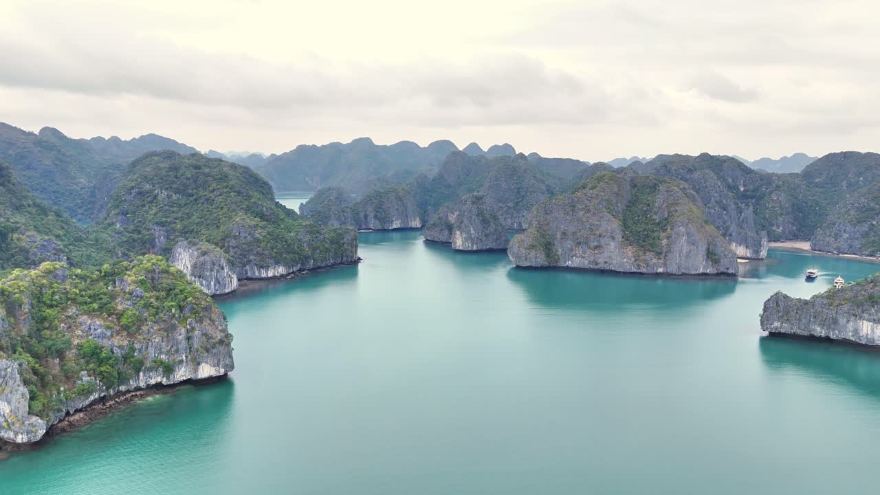 Turquoise waters surround towering limestone islands in Ha Long Bay, Vietnam, with a wide open bay