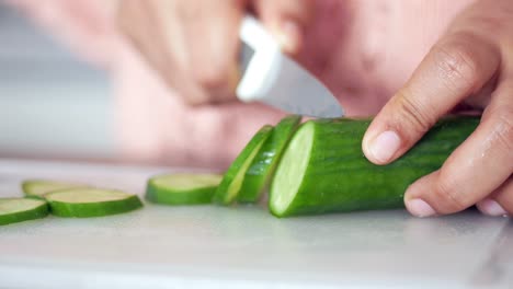 Young women cutting cucumber on chopping board
