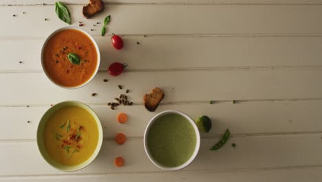 video of diverse cream vegetable soups with ingredients lying on white surface