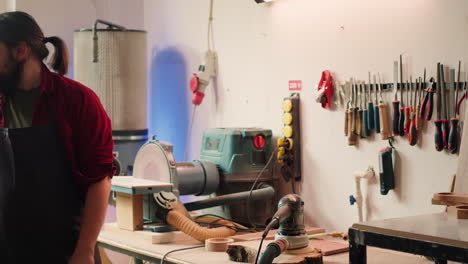 Man-wearing-protective-equipment-while-using-angle-grinder-to-sander-plank