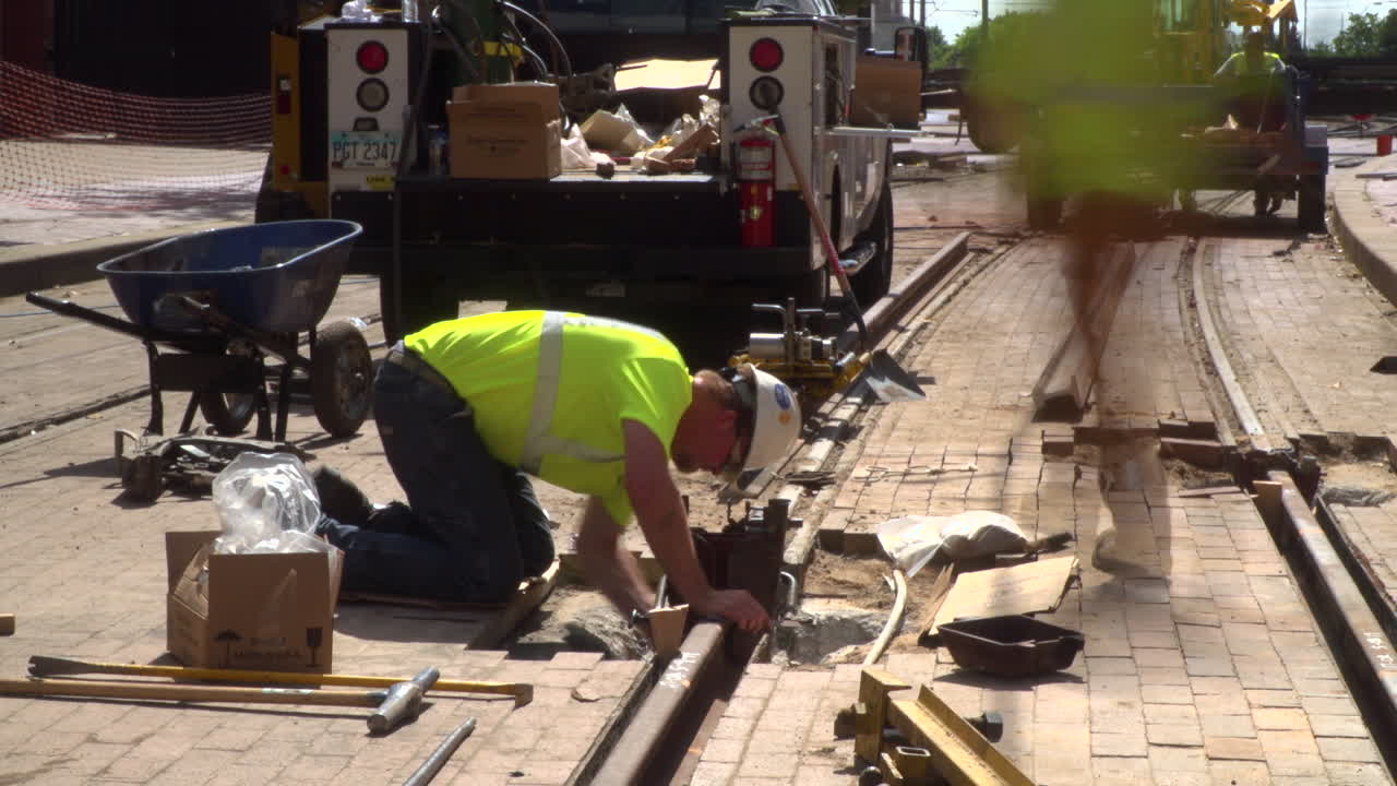 Time lapse video of construction workers laying new railroad tracks in a city.
