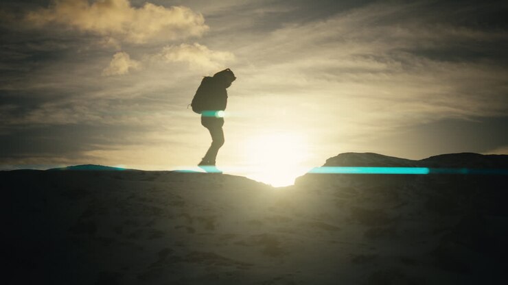 Silhouette shot of an individual walking across the Lovstakken mountain with lens flare