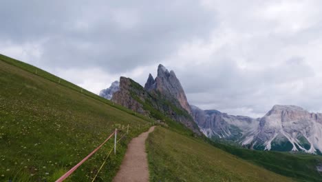 hiking trail in the mountain with seceda mountain peak in the background in bolzano, south tyrol, italy