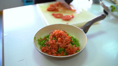 tomates picados y puerros en una sartén sobre la mesa - enfoque selectivo