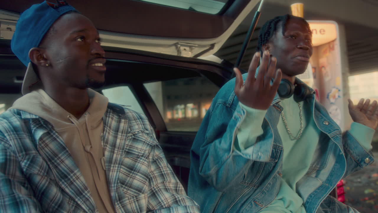 세 명의 흑인 친구들이 미소 짓고 다리 에서 차로 얘기하고 있습니다.