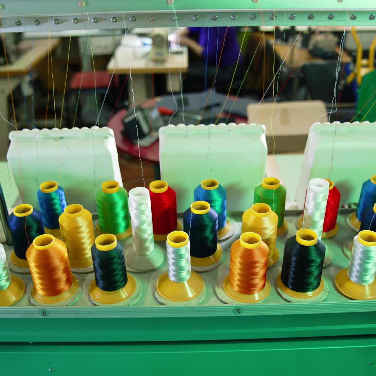 Industrial machines with colorful sewing thread. Rows spools of thread of different colors in the industrial sewing machine