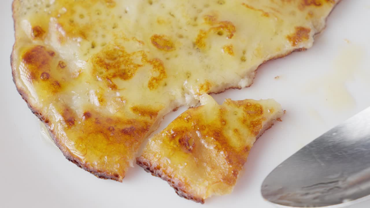 Spoon cutting a delicious handmade pancake on plate