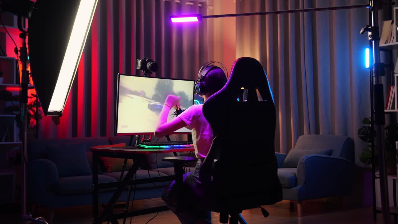 Back View Of Asian Girl Streamer Screaming Goal And Dancing Celebrating Winning Car Racing Game Over Network On Personal Computer.  Live Stream Video Game, Desk Illuminated By Rgb Led Strip Light