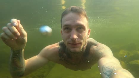 a young man films himself with an action camera as he takes a deep breath and dives into the cold norwegian water during a hot summer day