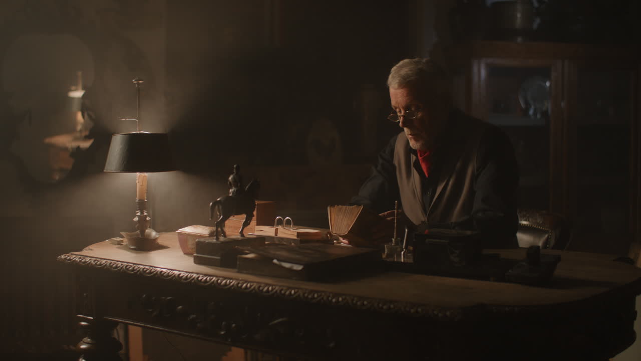 Old passionate man writes down a note in his office at night