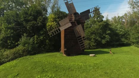 Historic,-wooden-and-renovated-mill-in-a-Polish-open-air-museum-surrounded-by-greenery-during-the-summer-in-Poland