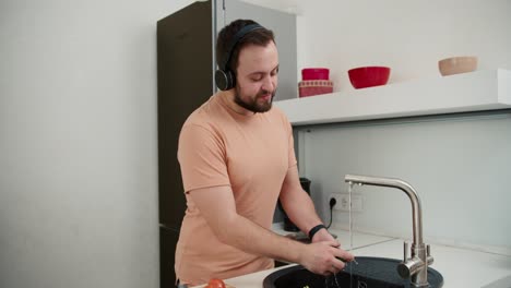 el dueño de casa escucha música dinámica en auriculares bailando en la cocina en casa