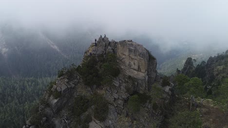 aerial pull away of people on the top of a mountain peak in mexico with clouds in the background