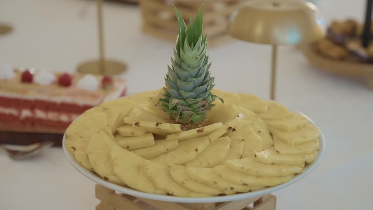 Piatto circolare con ananas a fette e decorazione a corona al centro su un tavolo da catering