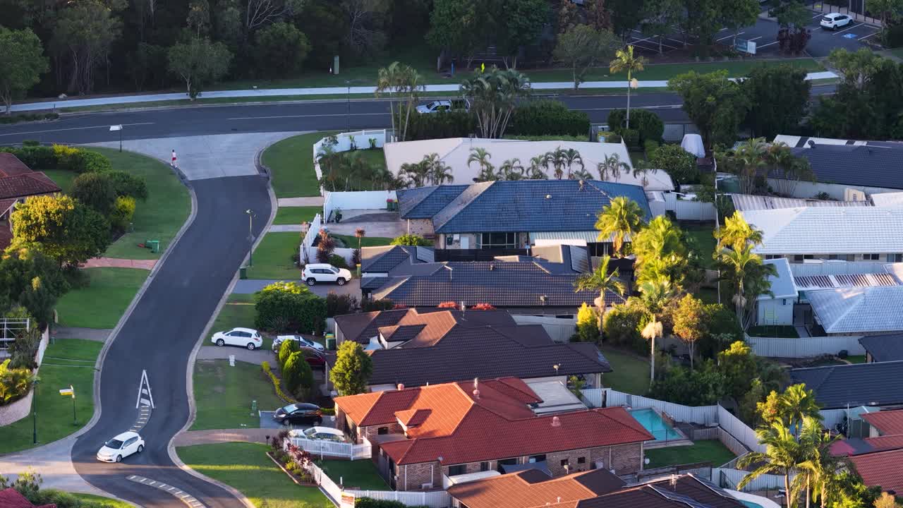 Drone shot captures residential streets and houses under warm golden hour lighting in Australia