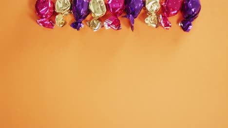 Close-up-of-multiple-halloween-candies-with-copy-space-against-orange-background