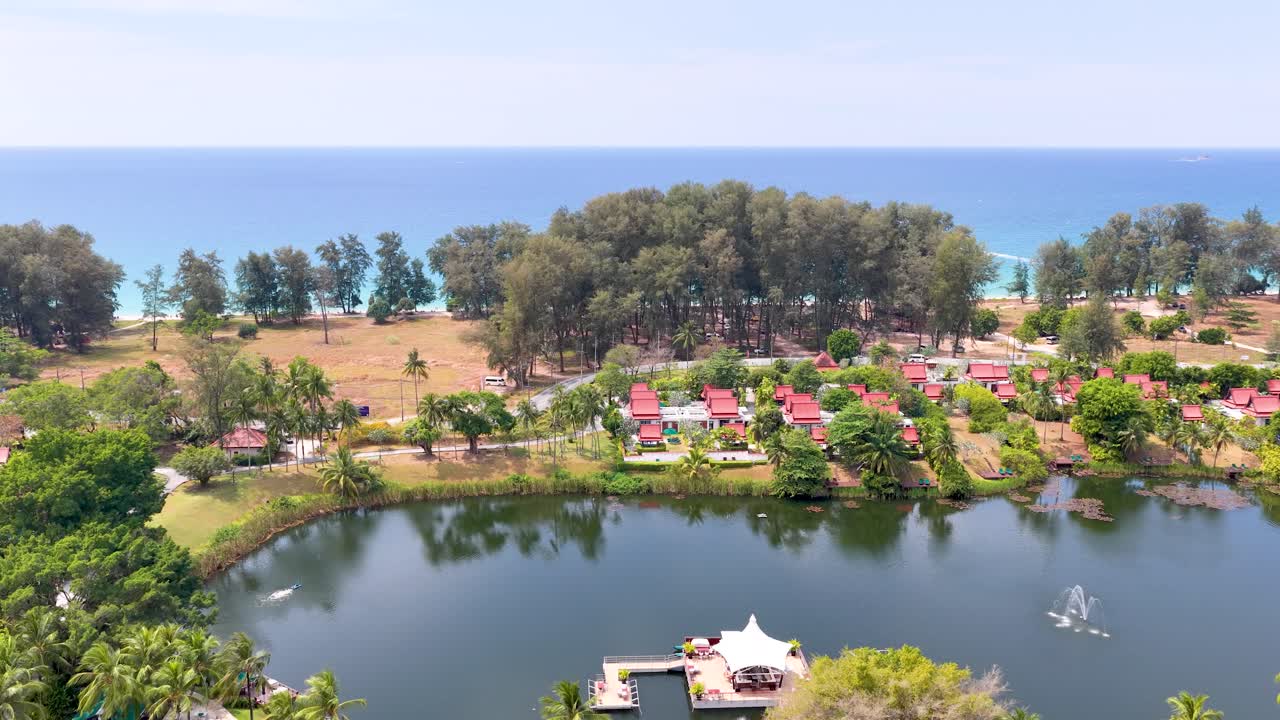 Kırmızı çatılı, göletleri ve golf sahası olan tropikal bir tatil köyünün drone görüntüsü.