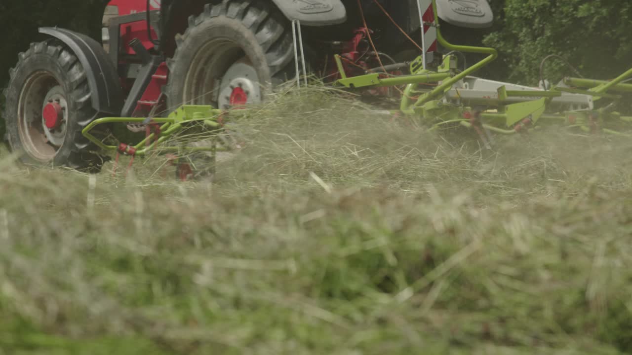 ángulo bajo del tractor cortando el césped en el campo de la propiedad