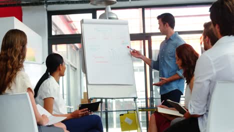 Man-discussing-design-on-white-board-with-colleagues-during-a-meeting