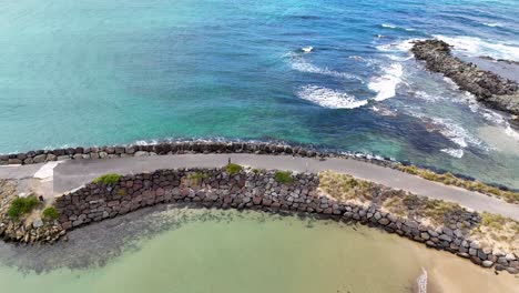 drone footage captures apollo bay's serene coastline with turquoise waters and rocky breakwaters under clear skies
