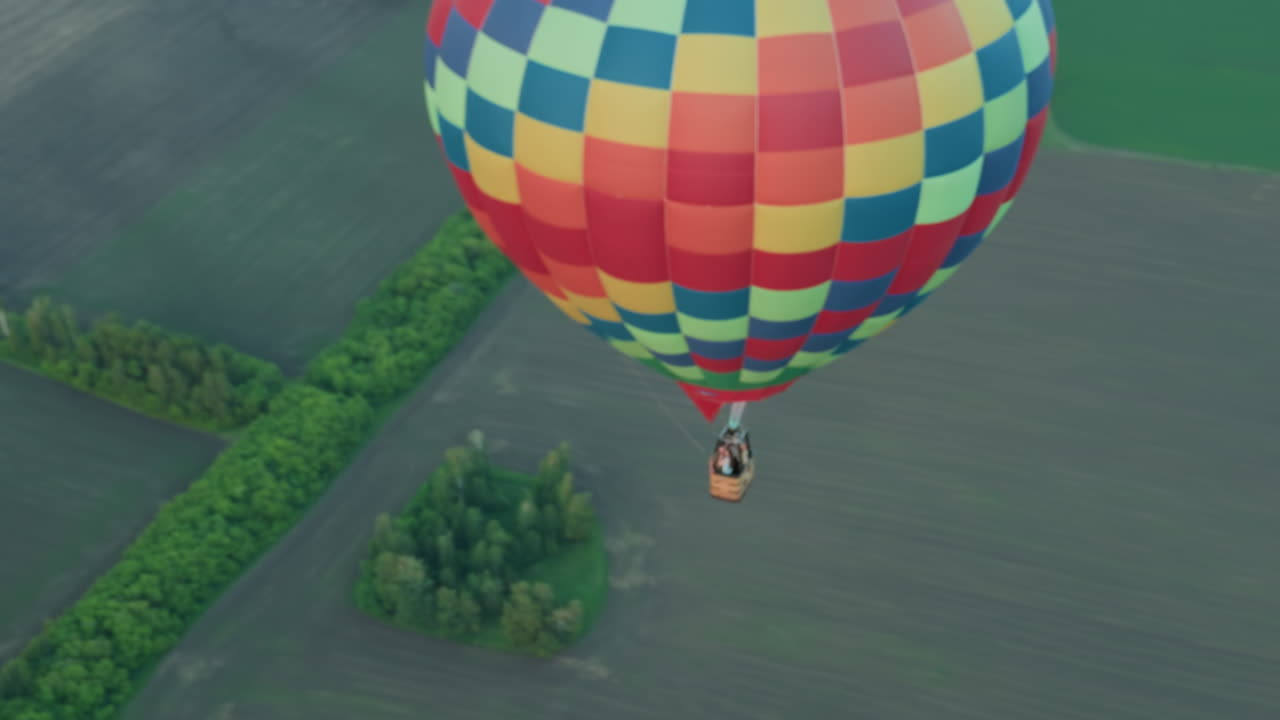 couple riding hot air balloon drifting over vast farmland at sunset while pilot ignites flame in burner for altitude change captured from aerial vantage showcasing serene adventure travel