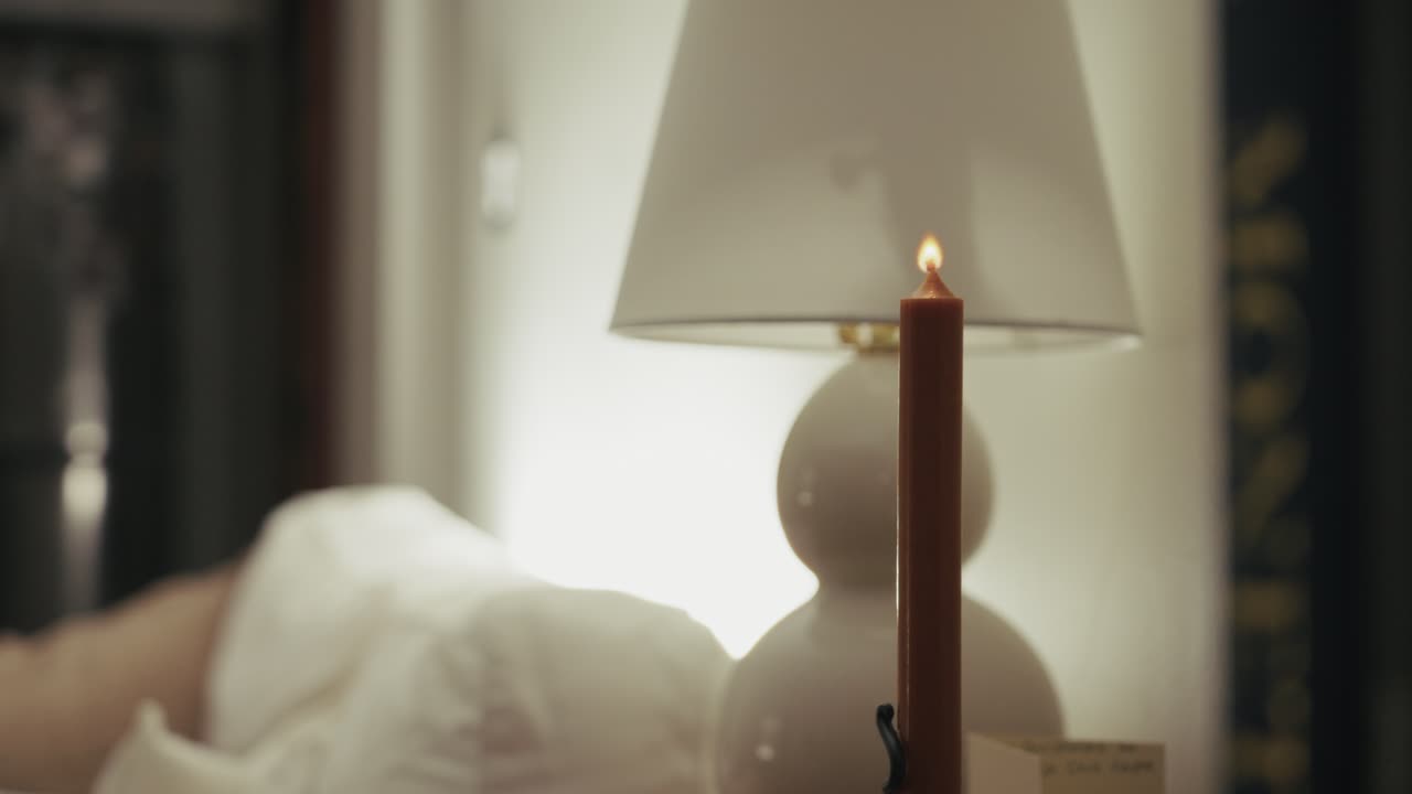 Una mano che accende una candela in una stanza accogliente crea un'atmosfera calda e tranquilla