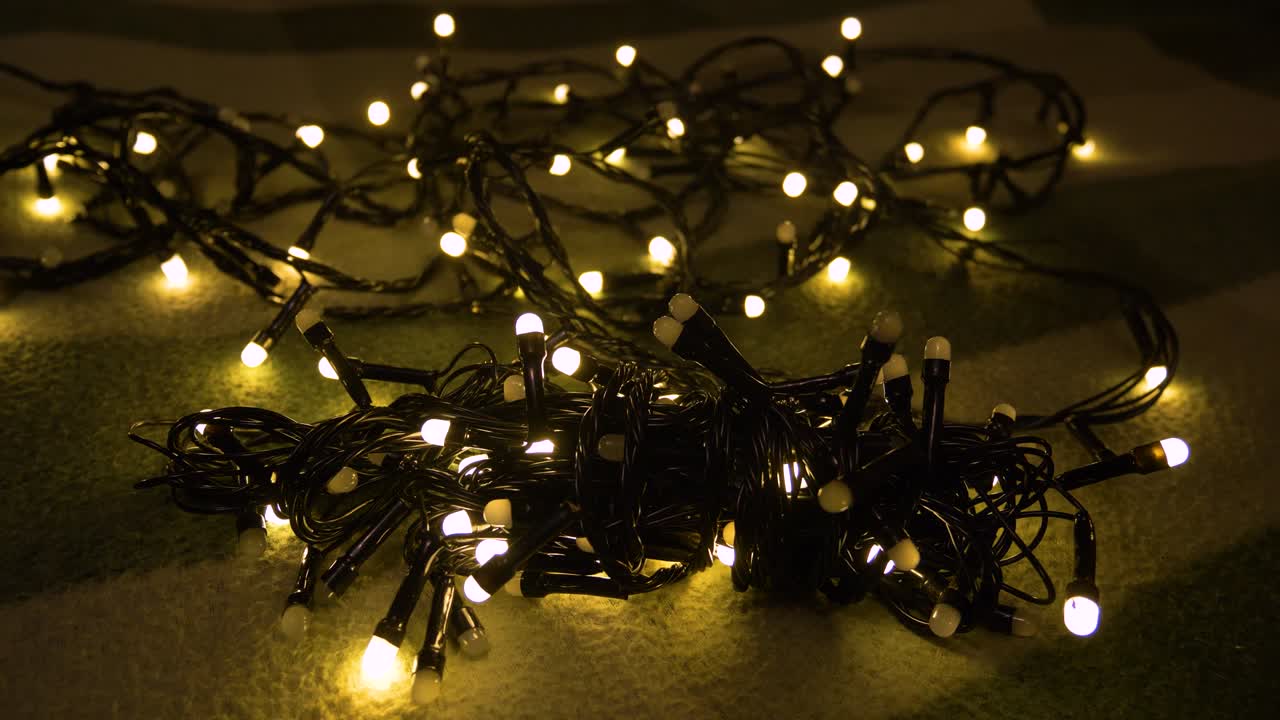 Bidikan close-up seuntai karangan bunga Natal dengan lampu emas di atas alas. Konsep Natal. Dekorasi rumah