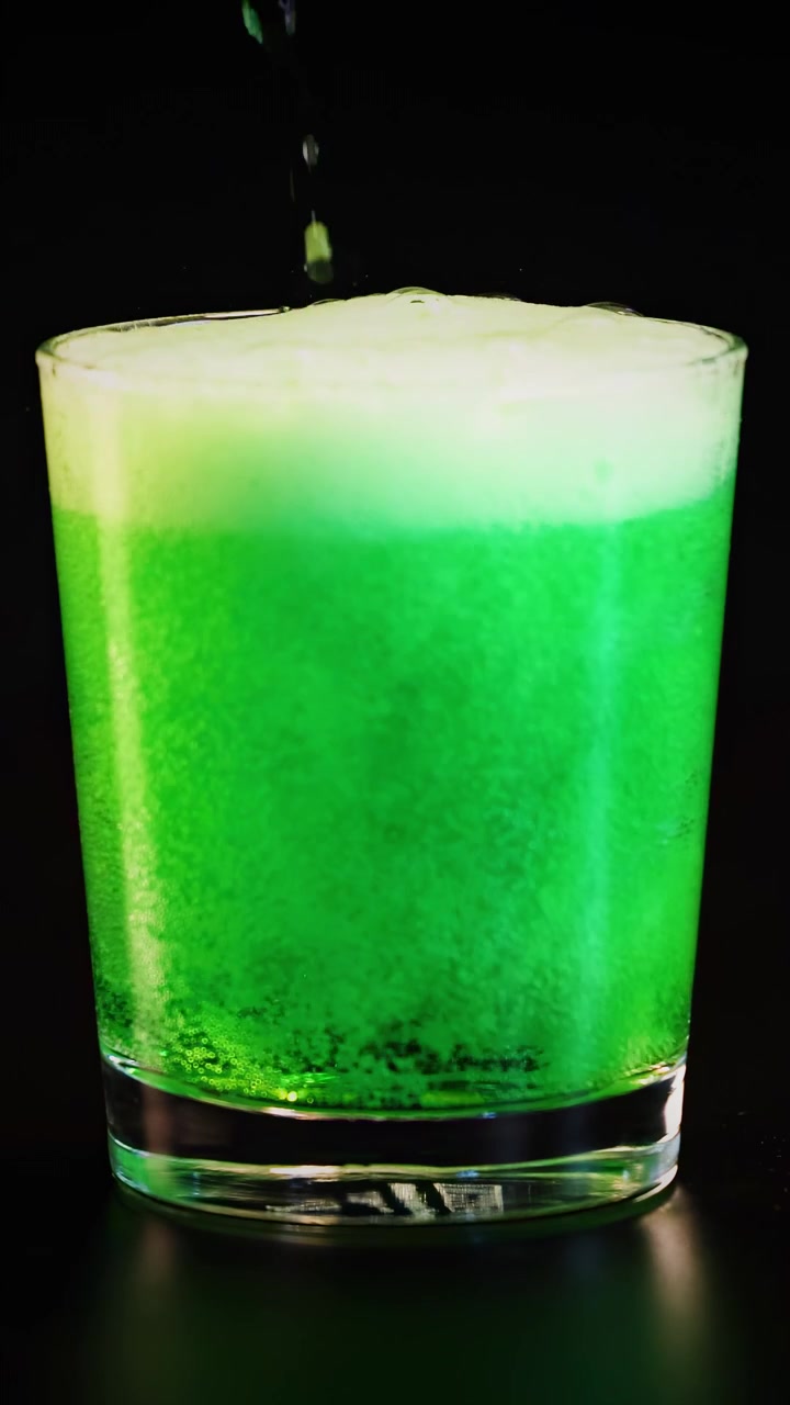 Bevanda verde versata, che frizza in un bicchiere