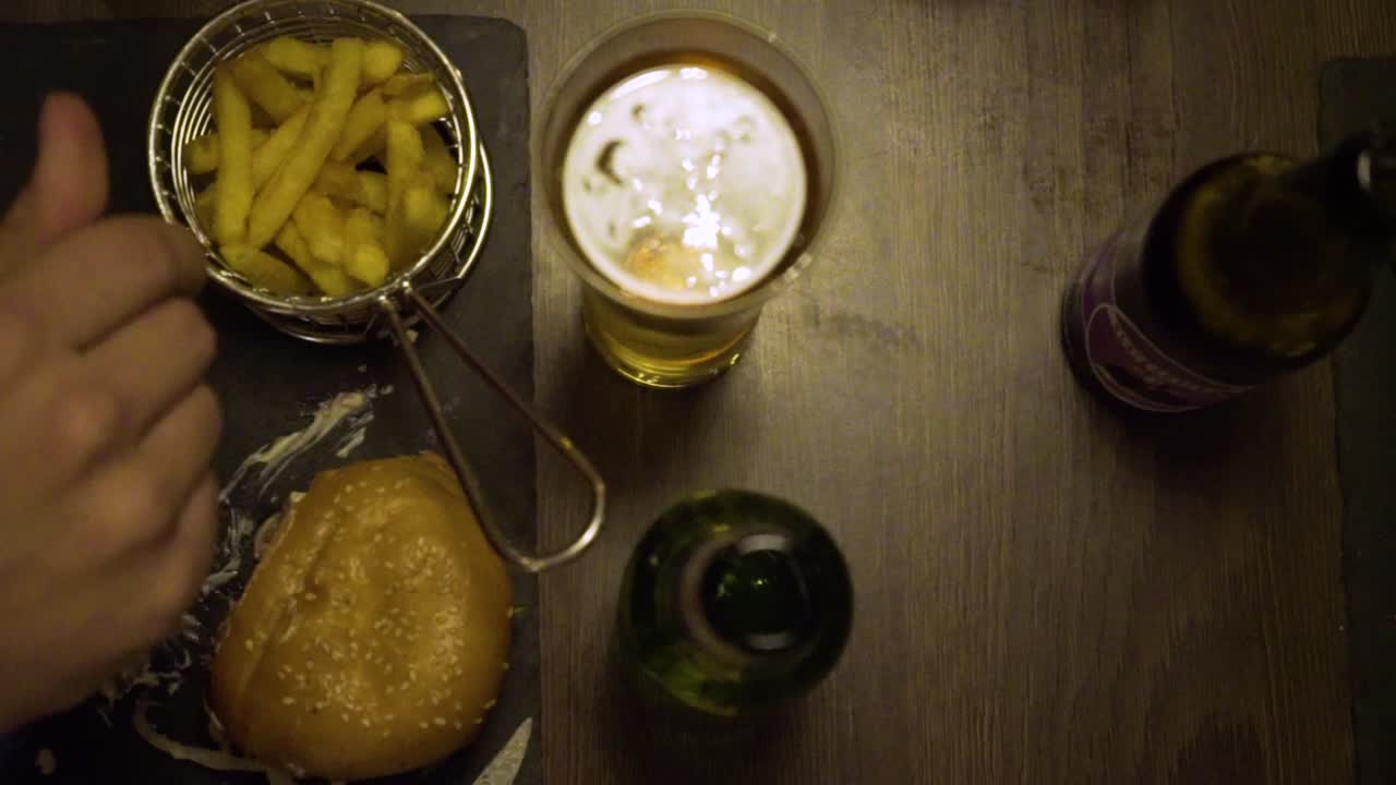 la cámara se desliza de derecha a izquierda sobre una mesa con hamburguesas y cerveza