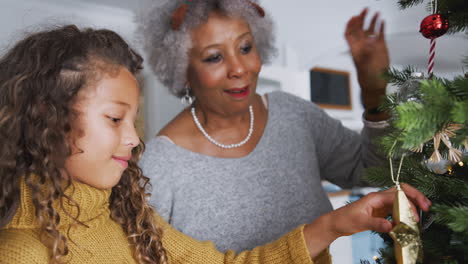 abuela y nieta decorando el árbol de navidad en casa juntos