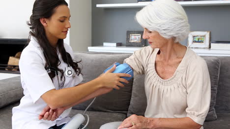 Home-nurse-checking-her-elderly-patients-blood-pressure