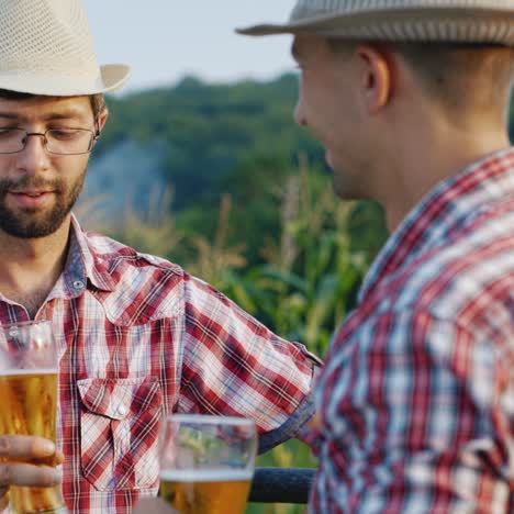 Two-farmers-drink-beer-at-a-fence-of-their-ranch-1