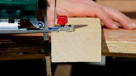 closeup of aman sawing wood with jigsaw