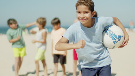 Front-view-of-cheerful-sportsman-holding-soccer-ball-under-arm