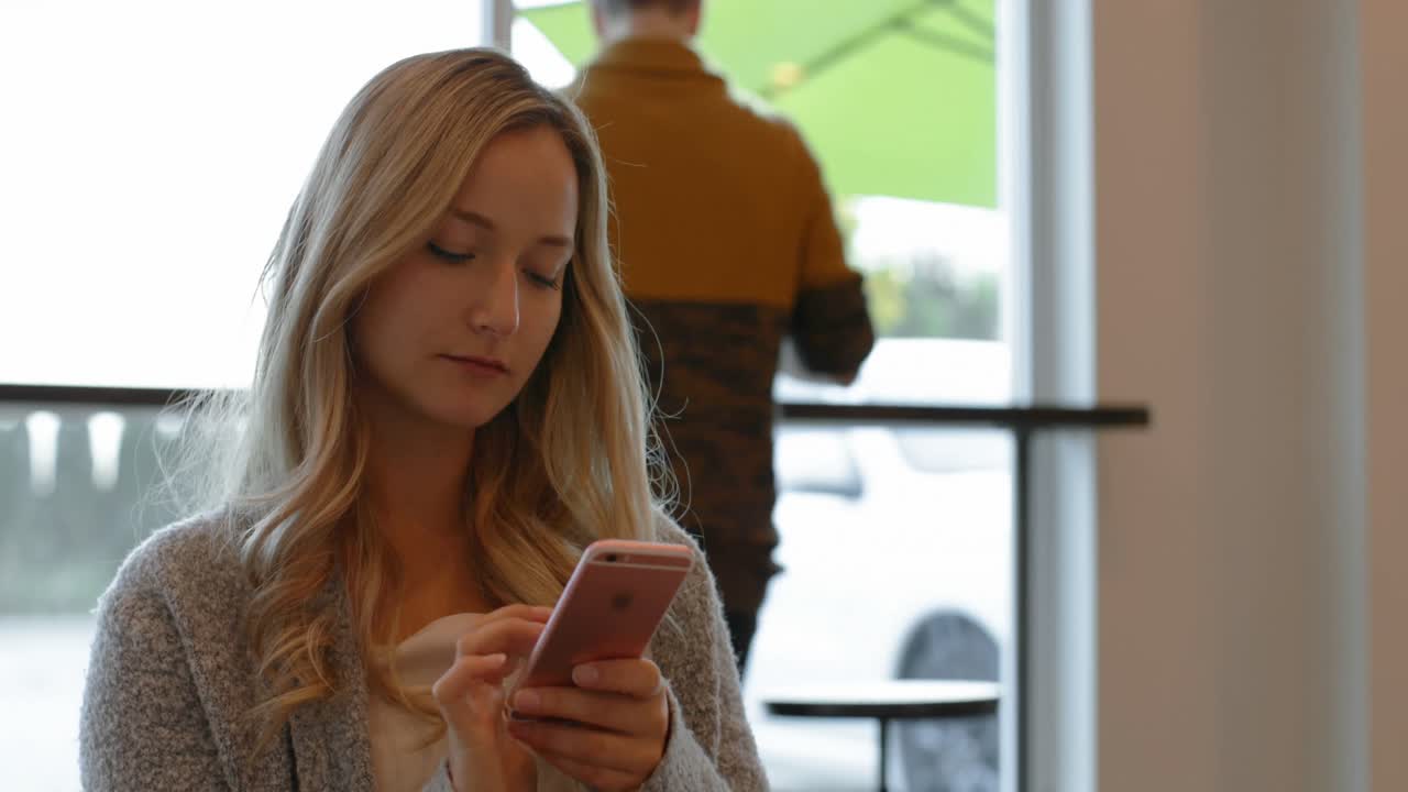 mujer hermosa usando teléfono móvil en el café 4k