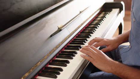 Mid-section-of-biracial-man-playing-piano-at-home,-slow-motion