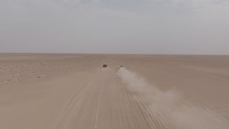 two off-road cars drive across a vast desert road to bar al hikman, oman