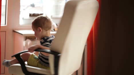 two year old boy is spinning on chair