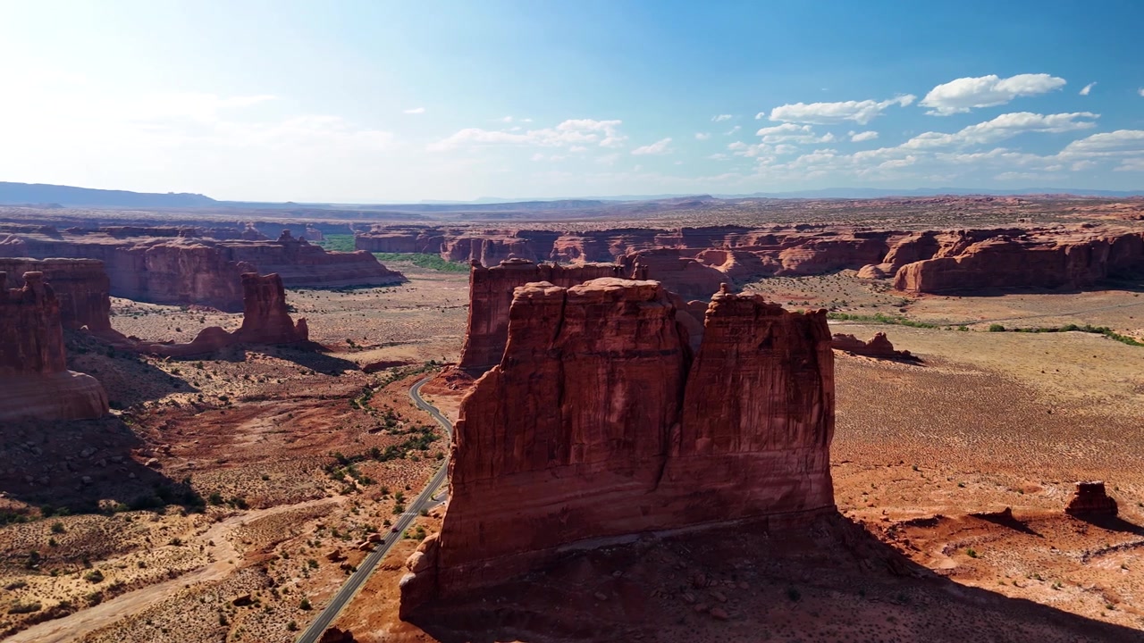Splendido filmato stock del Parco Nazionale di Arches, USA, durante un pomeriggio luminoso. La luce solare brillante illumina le maestose strutture di arenaria rossa e il paesaggio desertico sotto un cielo azzurro limpido.