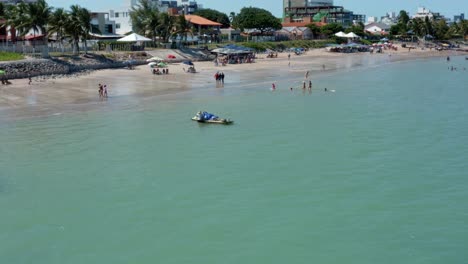 dolly in aerial drone shot of the tropical bessa beach in the coastal capital city of joao pessoa, paraiba, brazil with people enjoying the ocean and fishing boats at shore on a warm sunny summer day