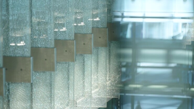 Close up textured glass wall panels with reflections inside modern office lobby