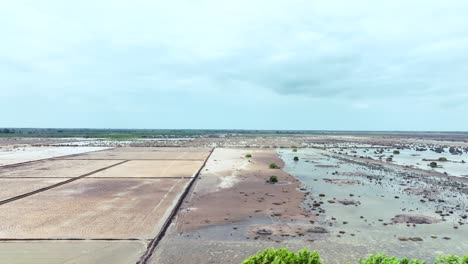 Aerial-parallax-shot-of-a-barren-land-surrounded-by-flooded-fields-of-Golarchi-farming-in-Sindh,-Pakistan