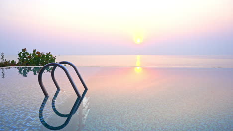 view from an infinity pool to the setting tropical ocean sun