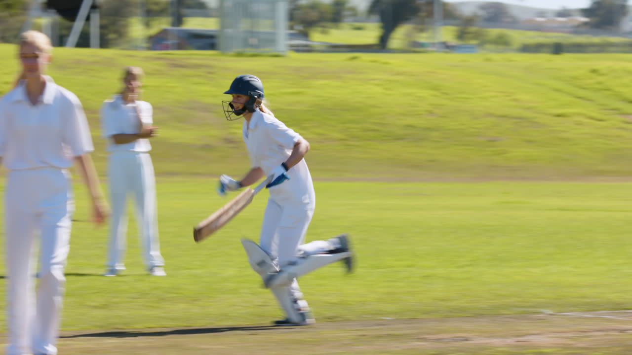 Playing cricket, female players running on field during match, wearing helmets